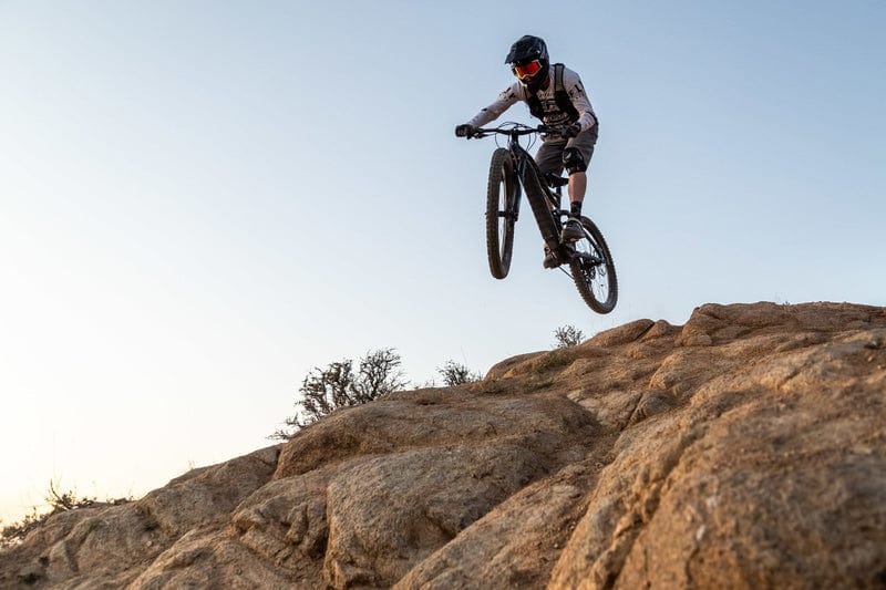 Niner WFO e9 e-Mountain Bike rider hitting jump on rocky trail on Fly Rides