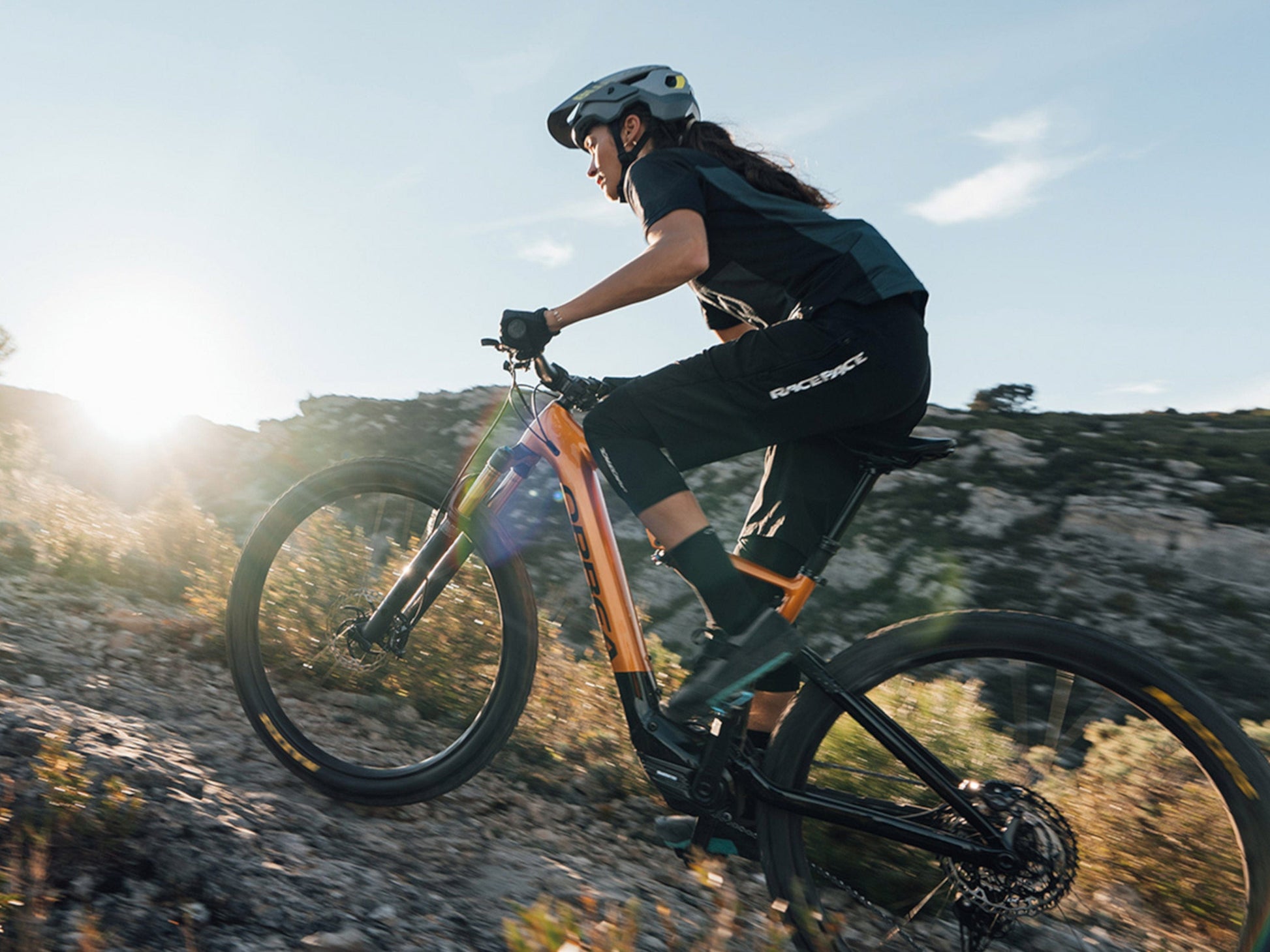 Woman riding uphill on an Orbea Rise Hydro H30 electric mountain bike
