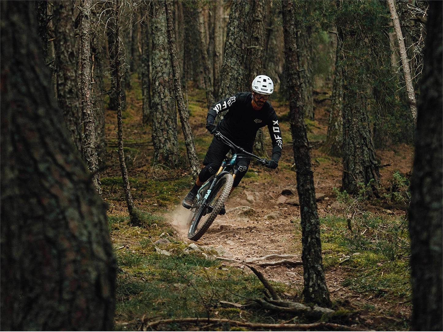 Action shot of an Orbea Rise M10 e-mountain bike on a trail in the trees