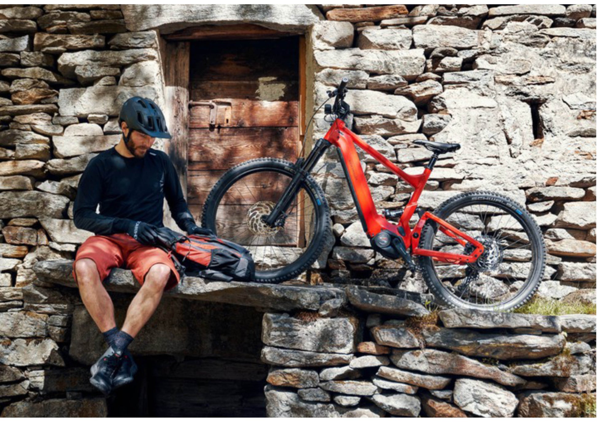 Riese and Muller Delite Mountain Touring eMTB full suspension man sitting with bike old stone house