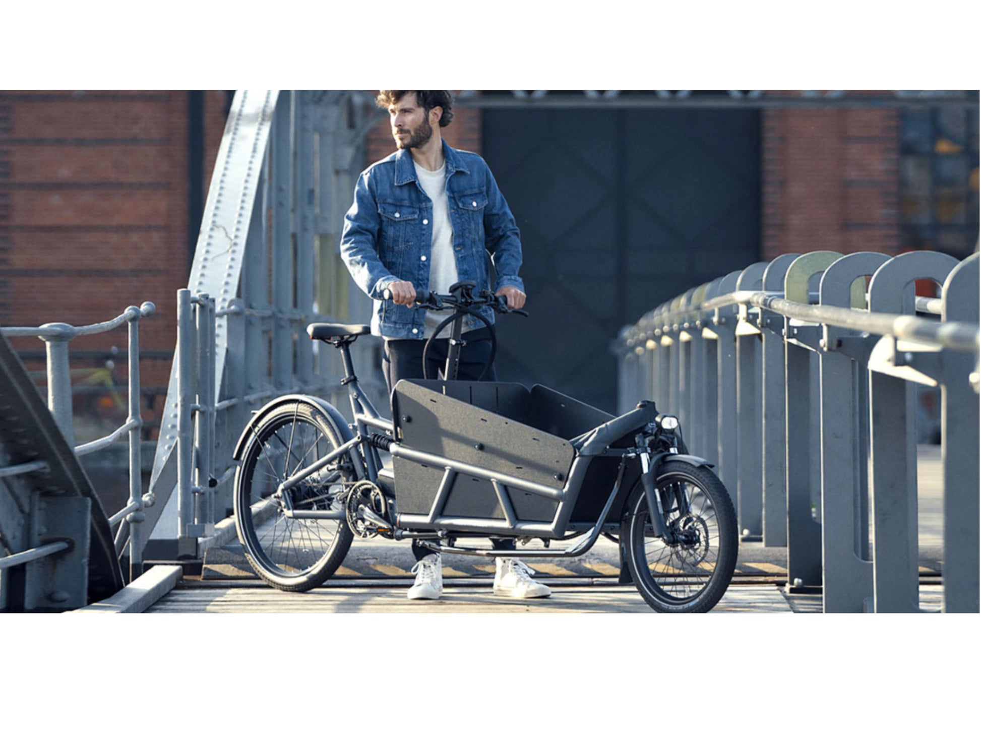 Riese and Muller Load 75 Rohloff Electric Cargo Bike full suspension. Man standing on bridge cargo area high sidewalls