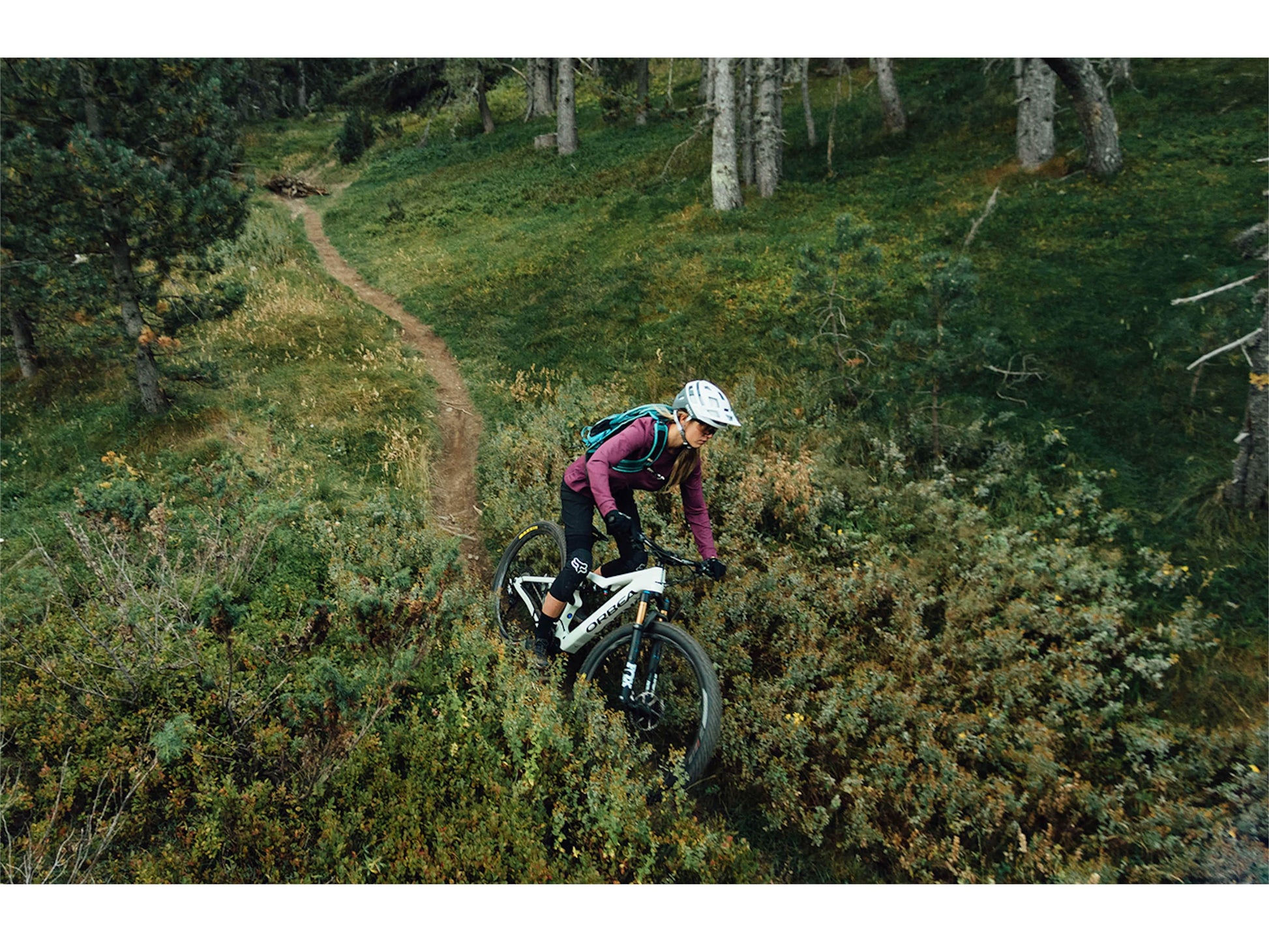 Woman riding an Orbea Rise M10 electric mountain on a forest trail